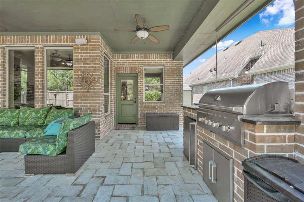 This covered outdoor patio with a built-in grill and brick accents is perfect for entertaining and relaxing.