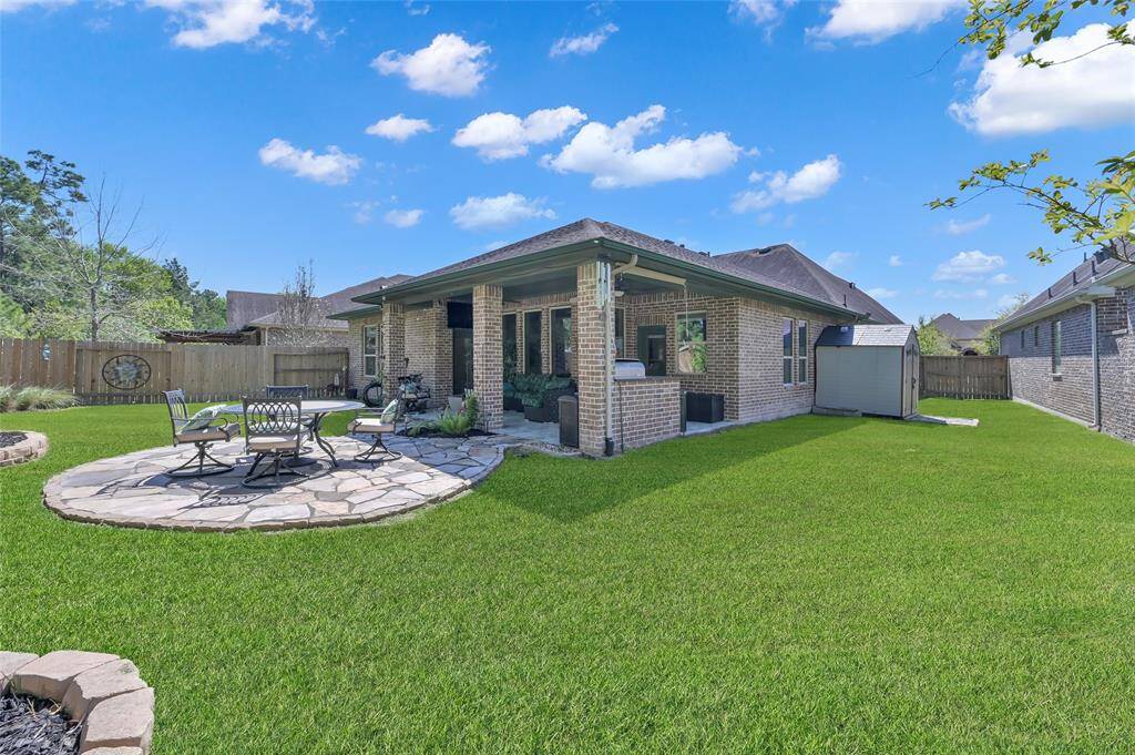 Perfect for outdoor entertaining and relaxation, this well-maintained backyard with a spacious lawn, a stone patio with outdoor seating, a covered area, and a small storage shed for extra storage.