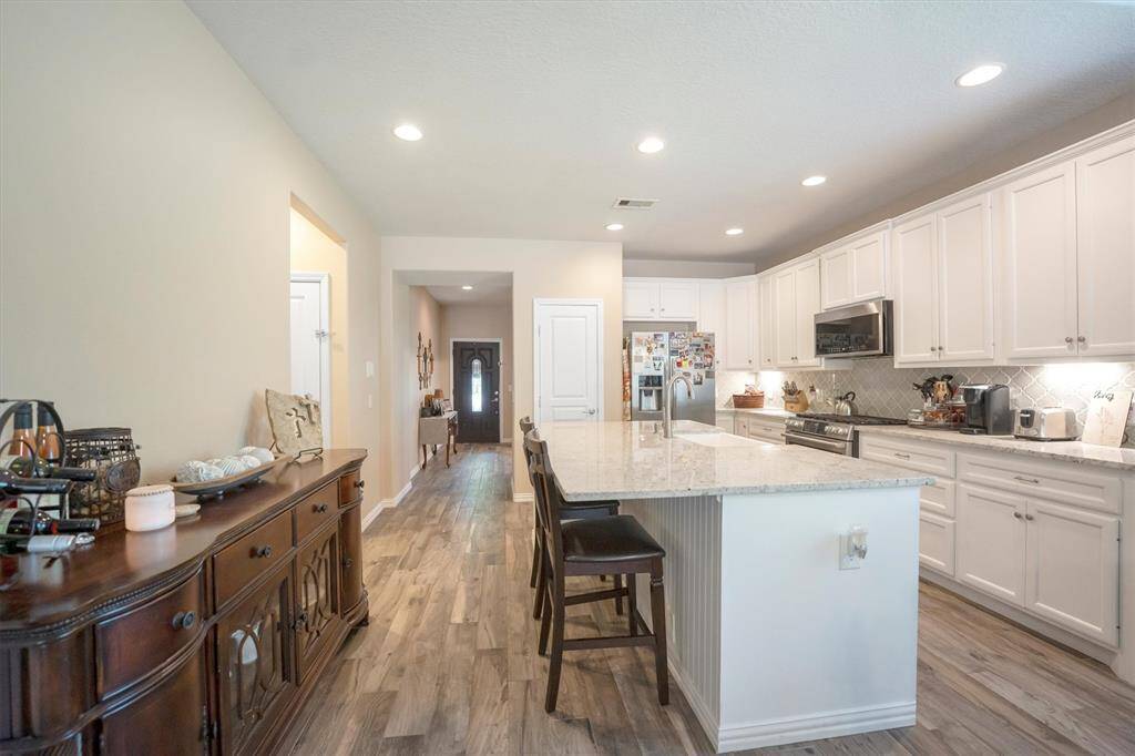 An oversized island takes center stage in this inviting kitchen, providing ample workspace for meal prep and bar seating that’s perfect for morning coffee, after-school snacks, or chatting with guests while cooking.
