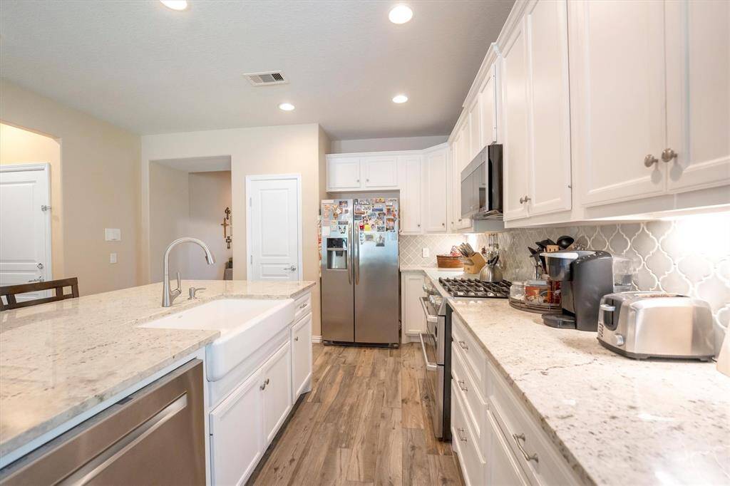 With wall-to-wall cabinetry, loads of counter space, and a spacious walk-in pantry, this kitchen is built for both storage and style. The sleek granite countertops, designer tile backsplash and under-cabinet lighting add just the right pop to keep things feeling fresh and inviting.