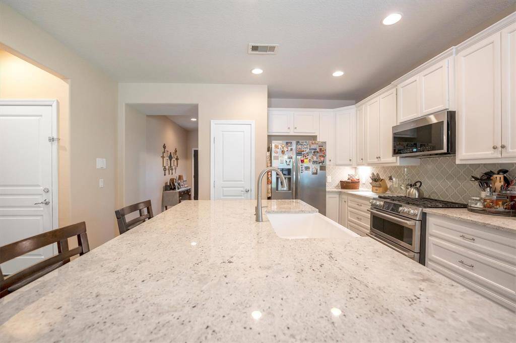 This kitchen shines with crisp white cabinetry, gleaming granite countertops, and a stunning oversized island complete with a farmhouse sink and bar seating. It’s the perfect blend of style, space, and everyday function.