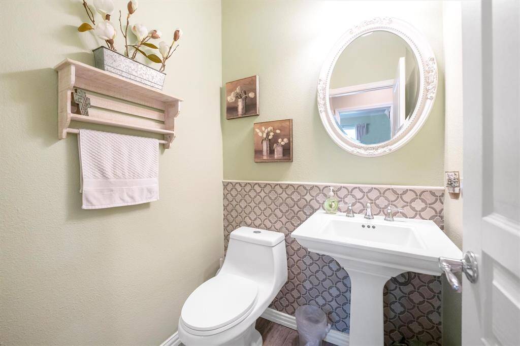 The first-floor powder bathroom is convenient for guests with a pedestal sink and a stylish mirror above.