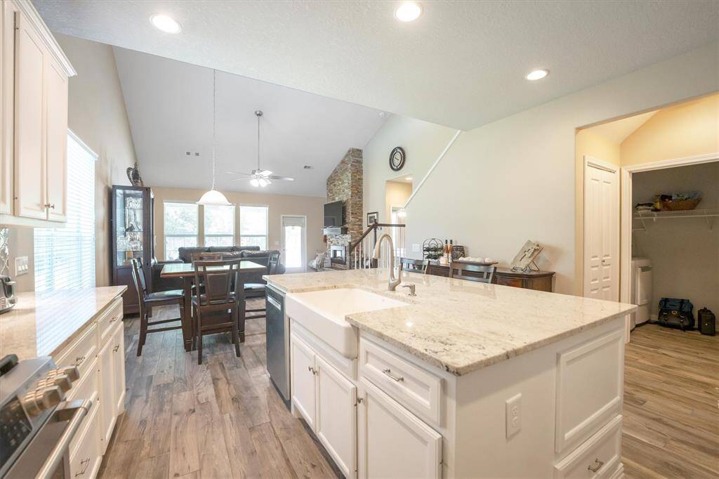 Designed for connection and convenience, this stunning kitchen flows effortlessly into the dining and living areas. A large center island with a farmhouse sink and bar seating anchors the space, while granite countertops and crisp white cabinetry add timeless style. Whether you're preparing meals or spending time with loved ones, this open-concept layout offers comfort and functionality at every turn.