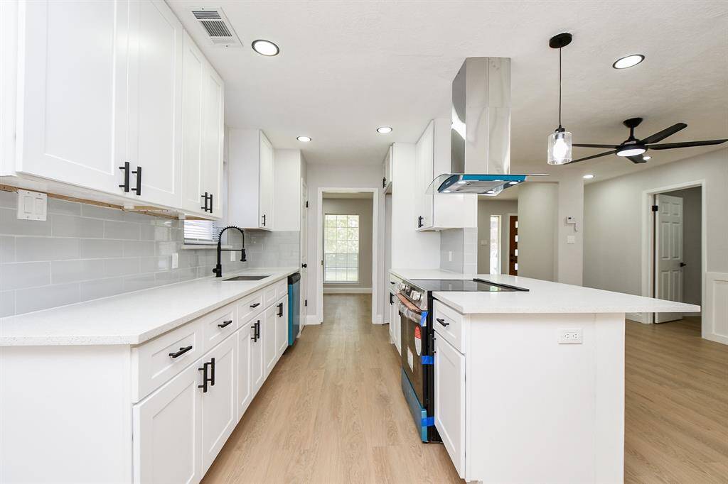 This modern kitchen features new appliances, a cooktop, and contemporary lighting fixtures, providing a bright and inviting space.