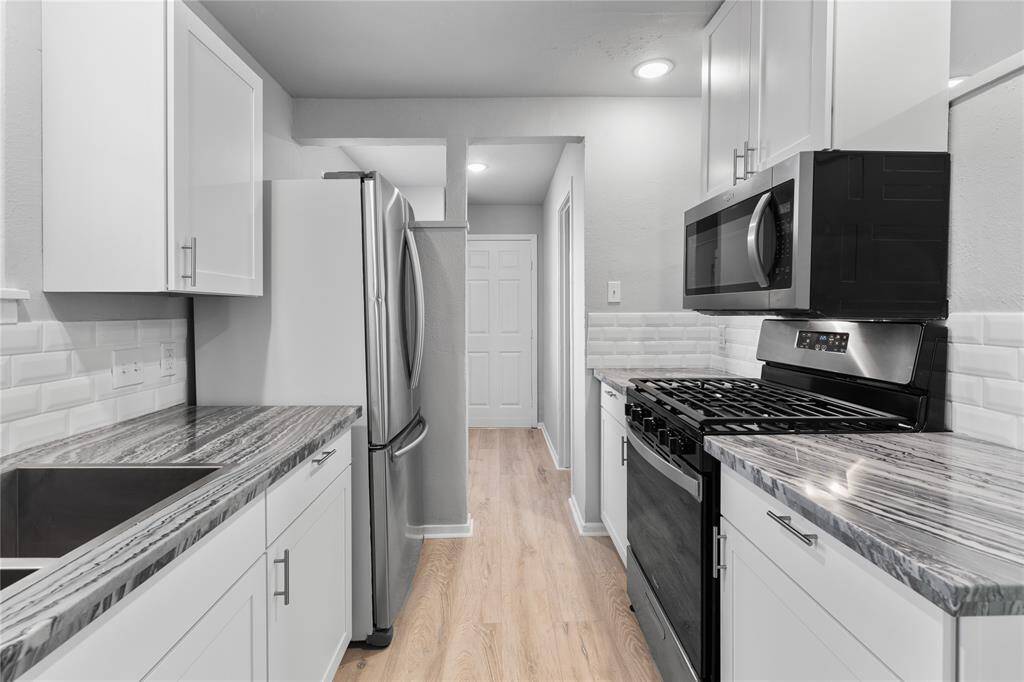 Updated kitchen with stainless steel appliances, elegant countertop, and timeless backsplash all enhanced from natural lighting.