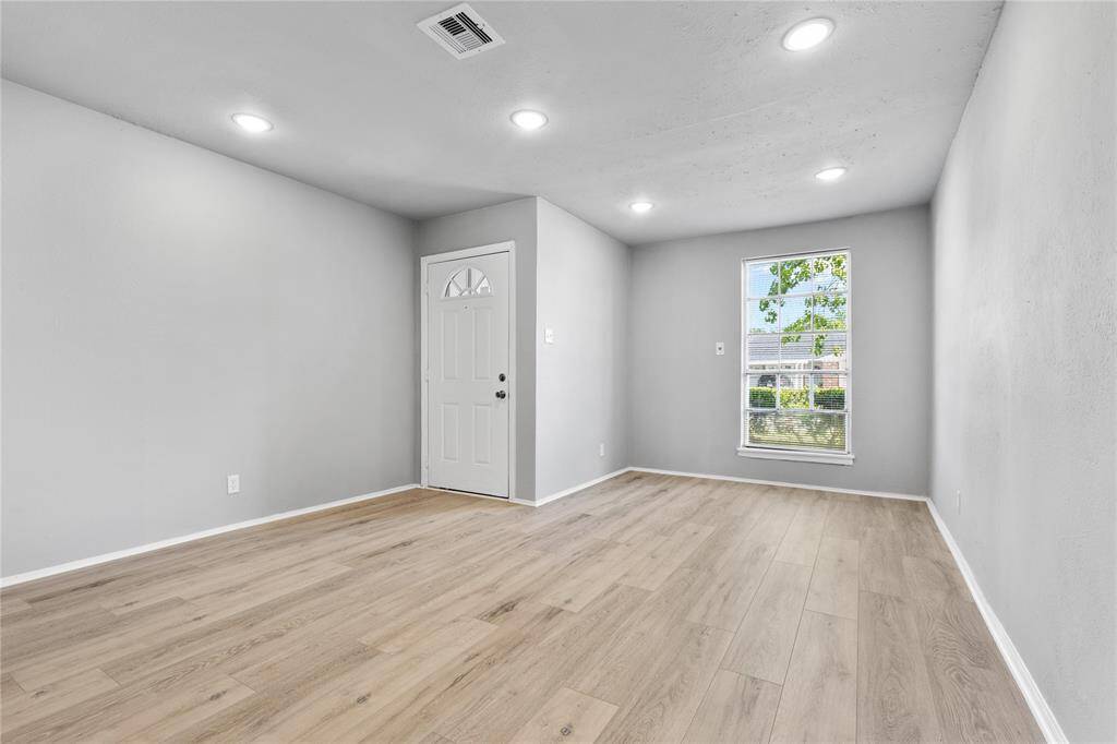 Bright and inviting living space with recessed lighting, and a large window that provides ample natural light.