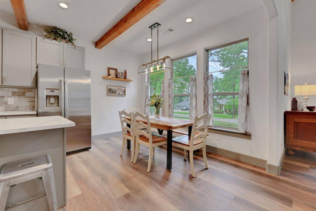 Large windows flood the space with natural light and provide scenic neighborhood views. Overhead, an industrial-style pendant light adds a touch of elegance to this dining area.