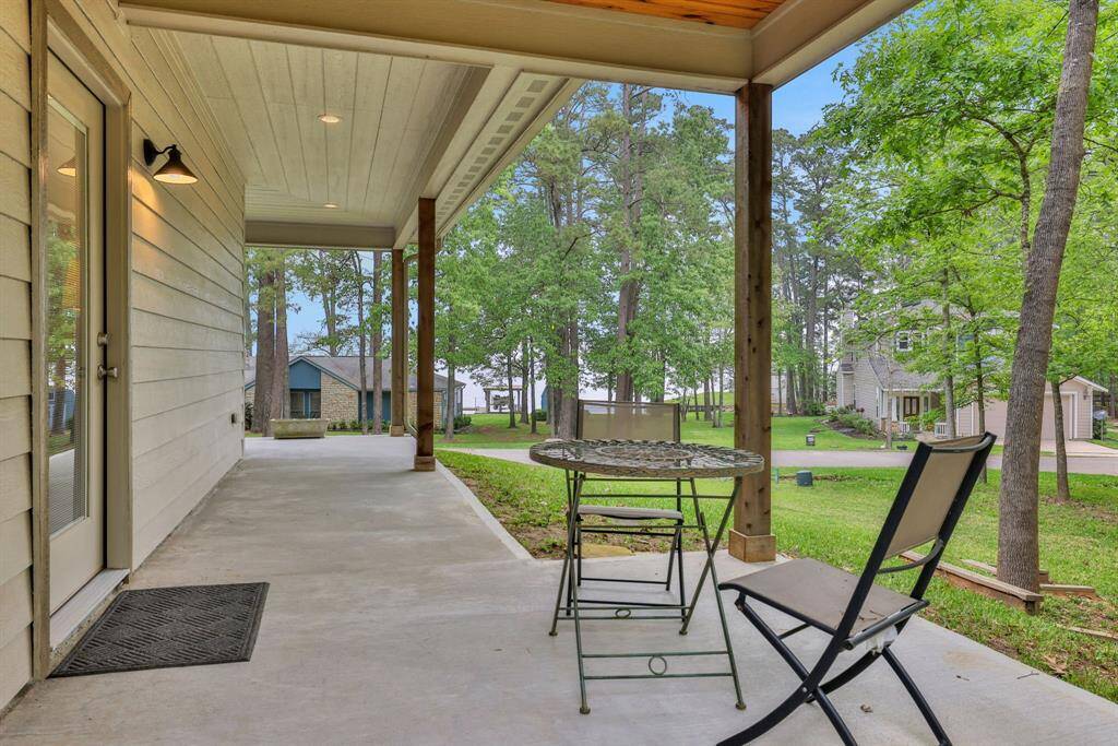 Walk out from the primary bedroom to this covered patio with beautiful views of the lake and mature trees providing a tranquil setting.