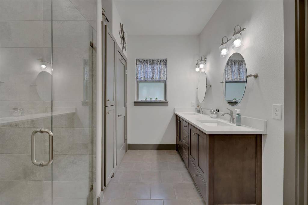 The primary bathroom features double vanities and the frosted window provides natural light but keeps the privacy.