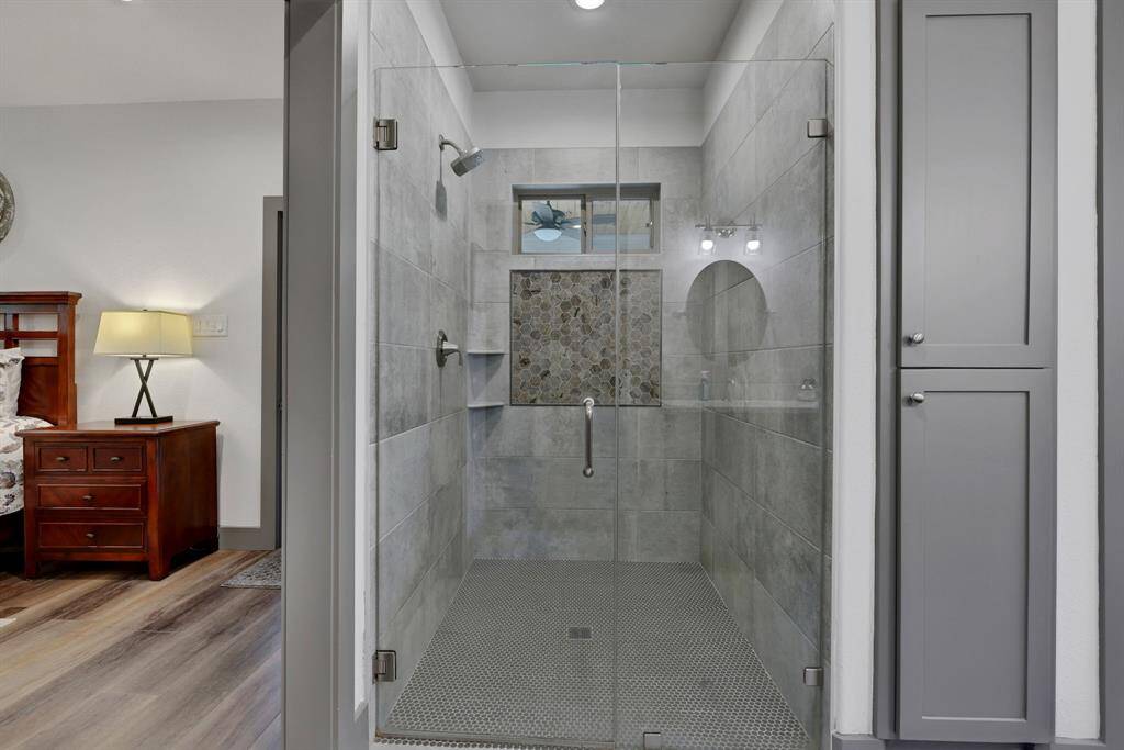 Primary bathroom features a tiled shower with sleek glass door and cabinets for easy storage!  Transom window allows for natural lighting.