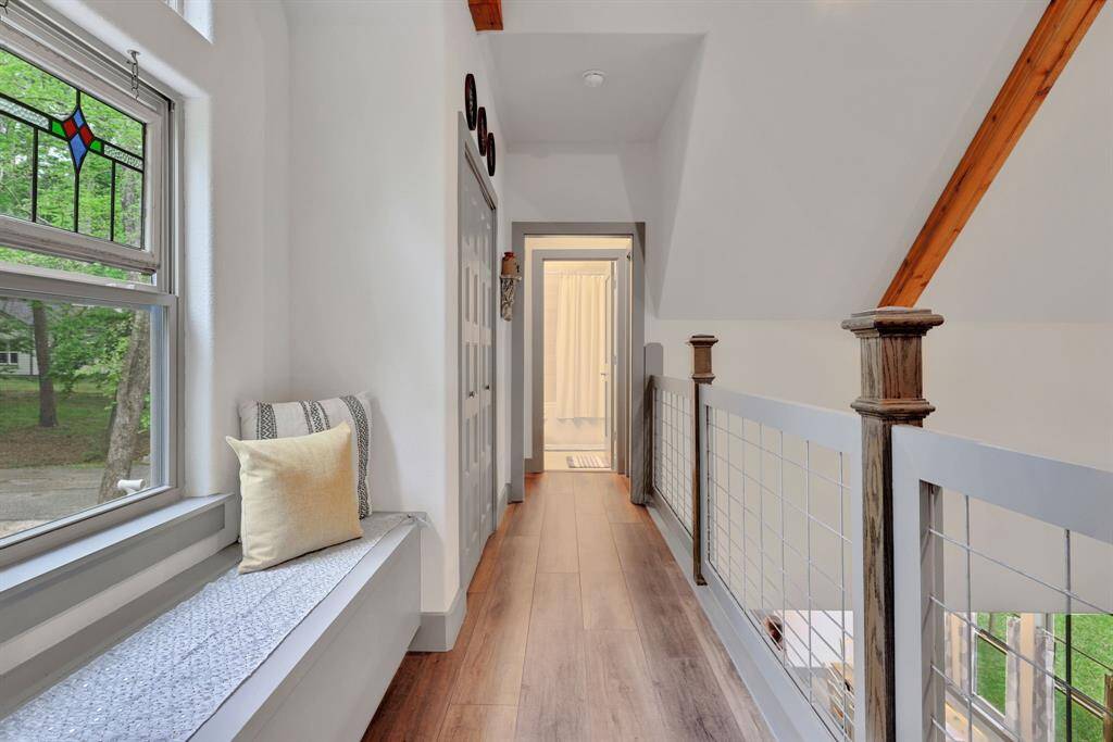 The modern farmhouse aesthetic continues with warm wood-look flooring, exposed beams, and cable railing overlooking the main living area.