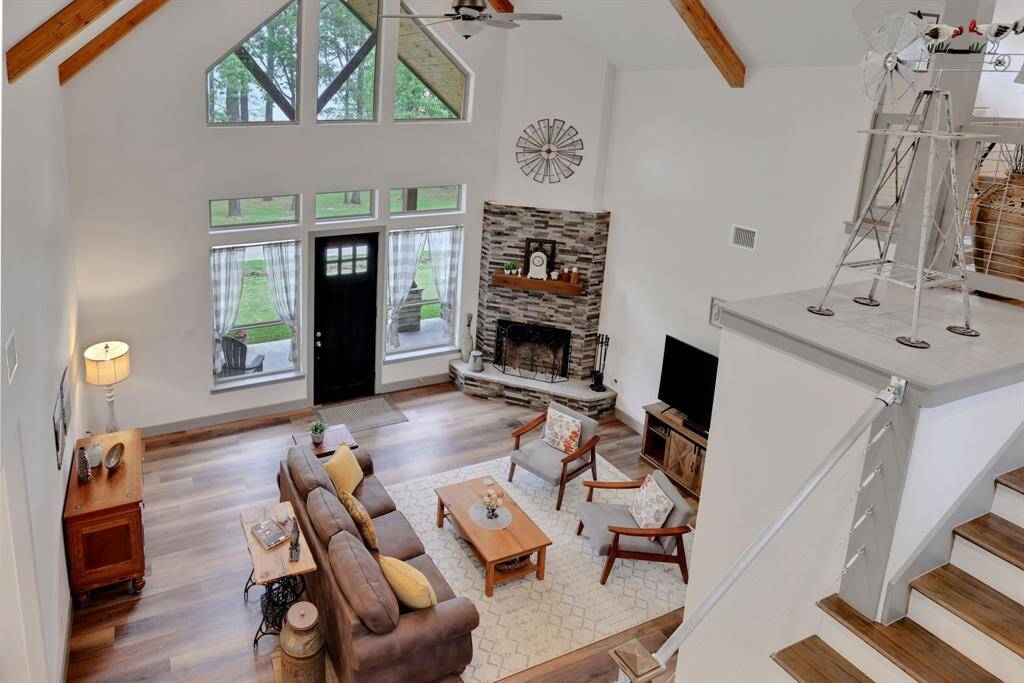 This stunning living room features soaring vaulted ceilings, a cozy wood-burning fireplace, and expansive windows that fill the space with natural light and offer serene views of Lake Livingston.