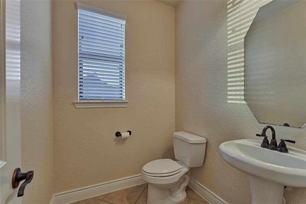 The half-bath is privately located in the hall just passed the home office and features tile flooring and a pedestal sink.