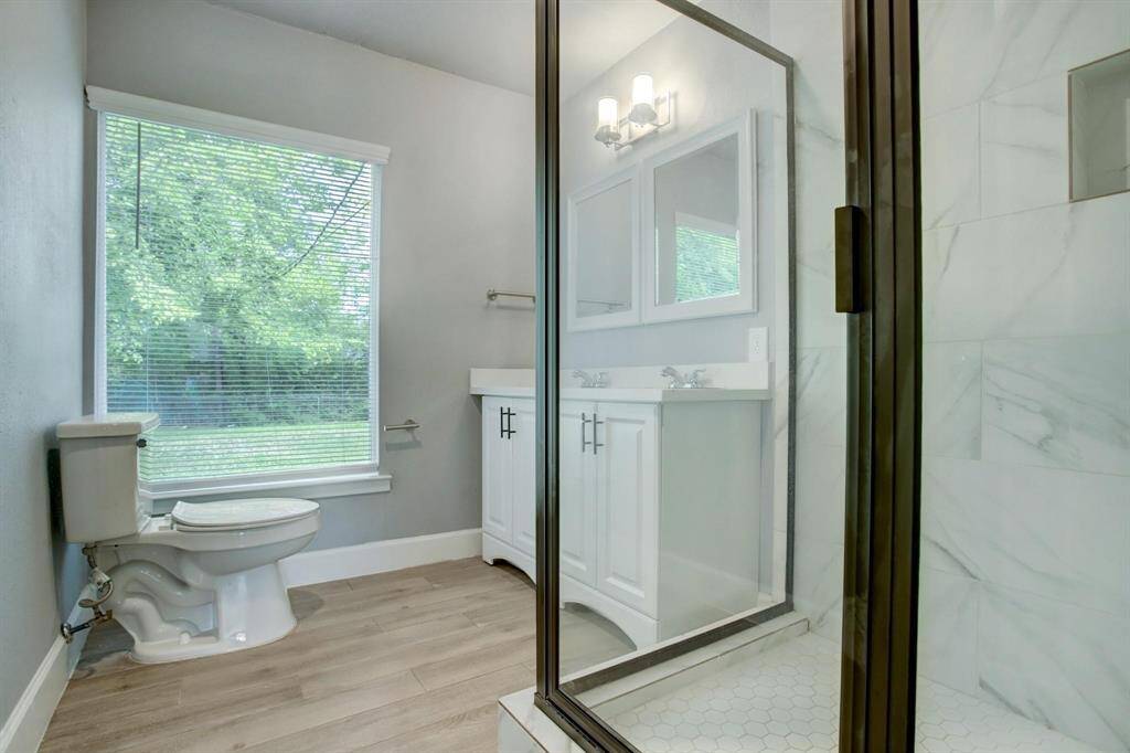 The primary bathroom boasts a spacious glass-enclosed shower, combining modern design with everyday comfort.