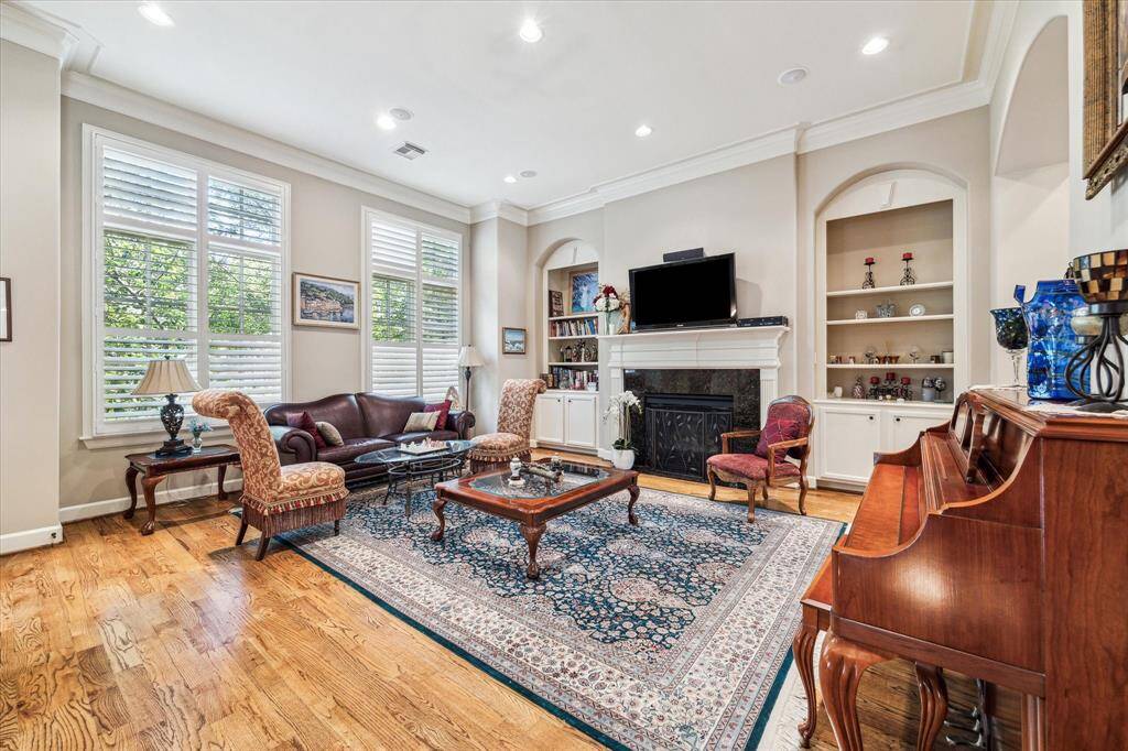 Second Level Living Room with high ceilings, hardwood flooring, crown molding, shutters, built-ins, gas log fireplace, recessed lighting and a Powder Bath..