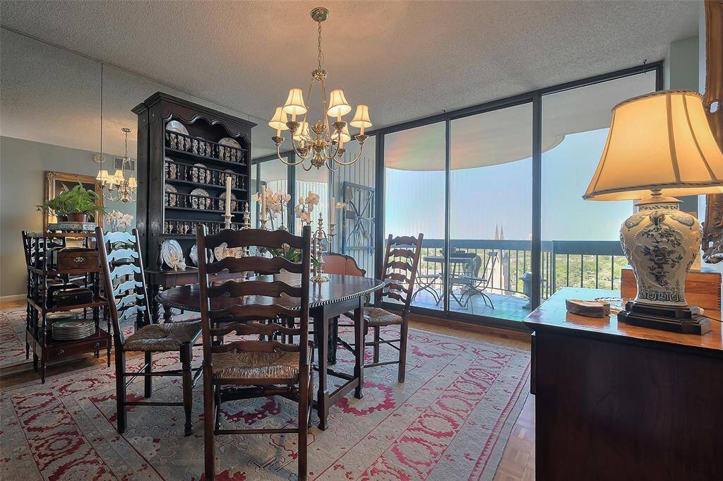 Charming dining room with elegant wooden furniture and a large, mirrored cabinet. The space is well-lit by a classic chandelier and a table lamp.