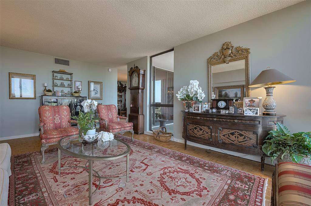 This cozy living room features elegant vintage decor with ornate furniture, a large mirror, and a grandfather clock.