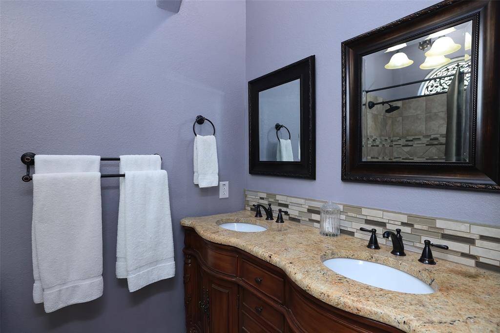 Located in the upstairs bedroom for another ensuite is this very pretty full bath with furniture style cabinets, double sinks and granite counters.