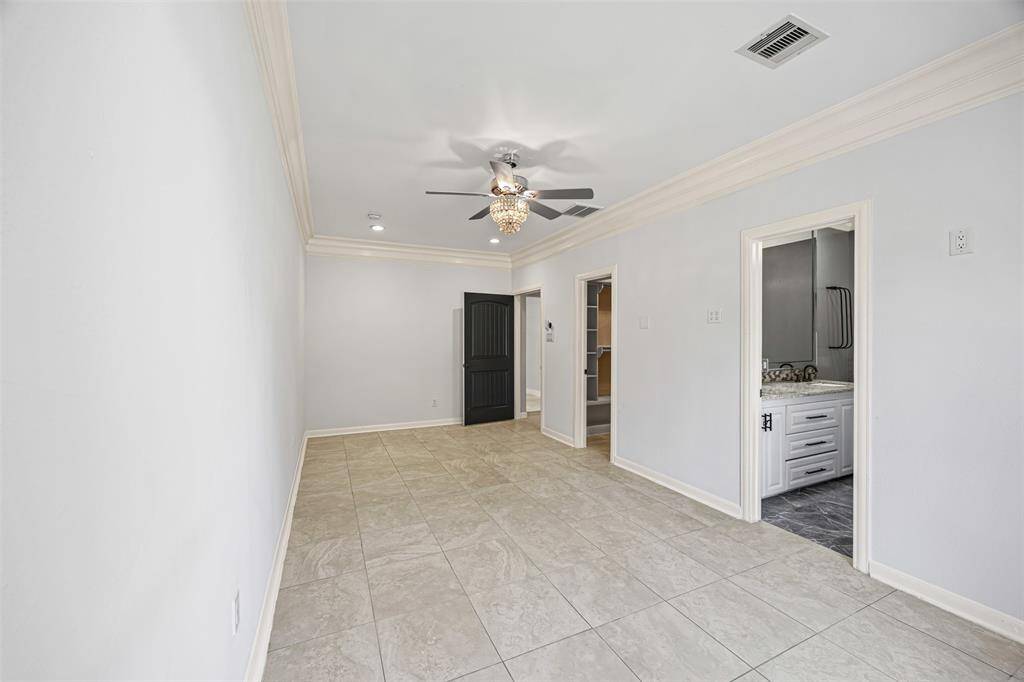 The owner’s suite offers elegance and serenity with crown molding, recessed lighting, and a chandelier fan, plus a spa-like bath with a jetted tub, separate shower, and his-and-hers custom vanities.