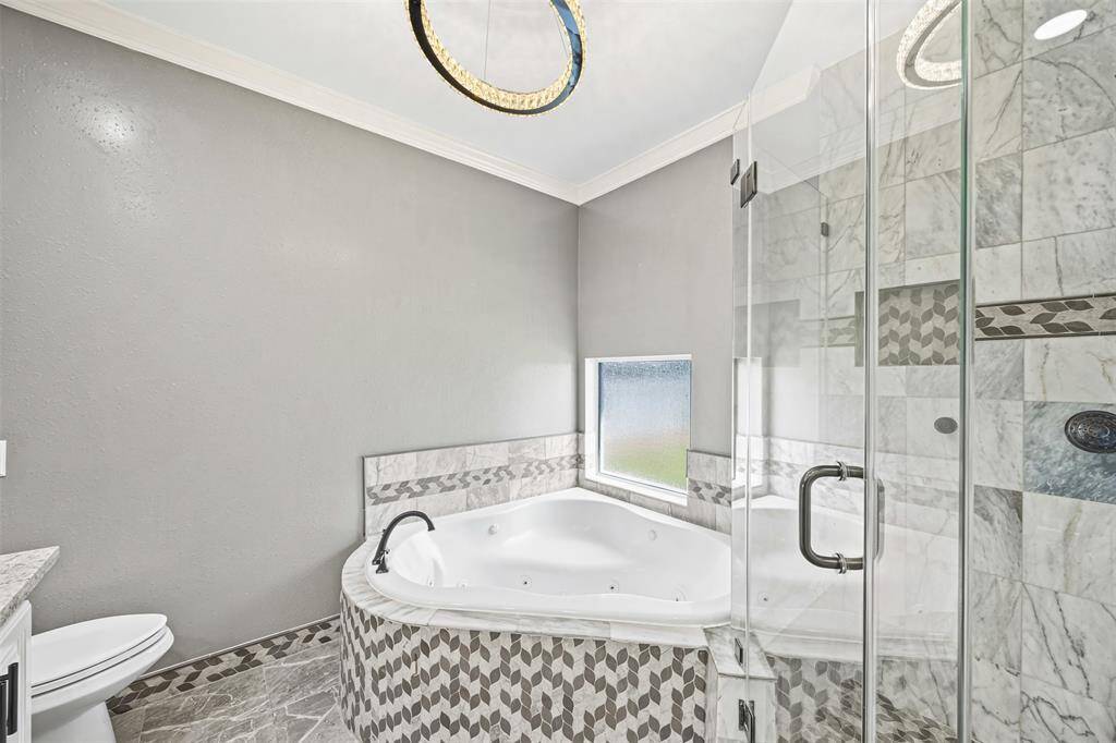 The owner’s suite offers elegance and serenity with crown molding, recessed lighting, and a chandelier fan, plus a spa-like bath with a jetted tub, separate shower, and his-and-hers custom vanities.