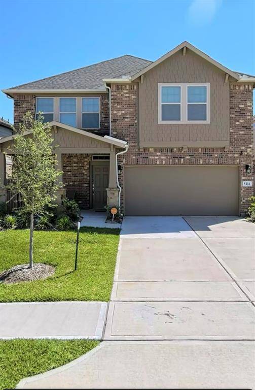 This is a modern two-story brick home with a two-car garage. It features a well-maintained front lawn, a small tree, and a welcoming entryway. The exterior combines brick and siding, providing a classic yet contemporary look.