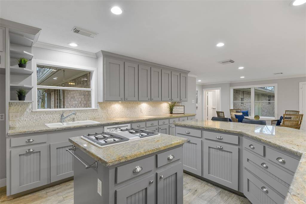 The updated cabinetry features a shaker-style finish that complements the beadboard base of the wrap-around island and the cabinets also offer under-cabinet task lighting along with ample prep space in this expansive kitchen.