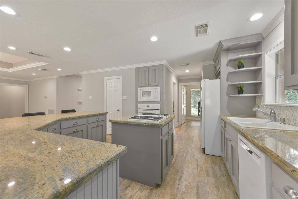 The chef of the house is certain to appreciate the roomy walk-in pantry, as well as the 4 burner Jenn-Air downdraft gas cooktop, convection oven built-in microwave, and dishwasher. A dual basin porcelain sink boasts a window with driveway views above it.