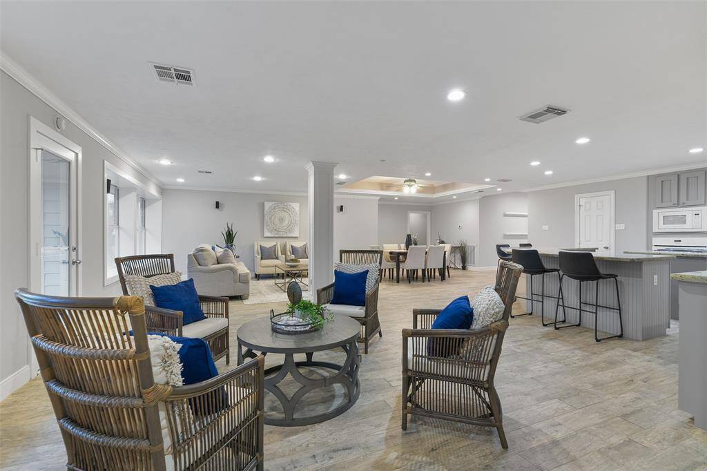 Along the far side of the kitchen and blending seamlessly into the family room, there is a generously proportioned gathering space with recessed lighting, wood-look tile flooring, crown molding, and an expansive cased window with a window seat.