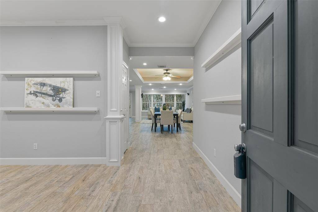 A brick and vinyl siding exterior makes way to a covered porch and a traditional 6-panel door that opens into this light and bright open-concept living space with neutral grey paint, wood-look tile floors, elegant moldings, and recessed lighting throughout.