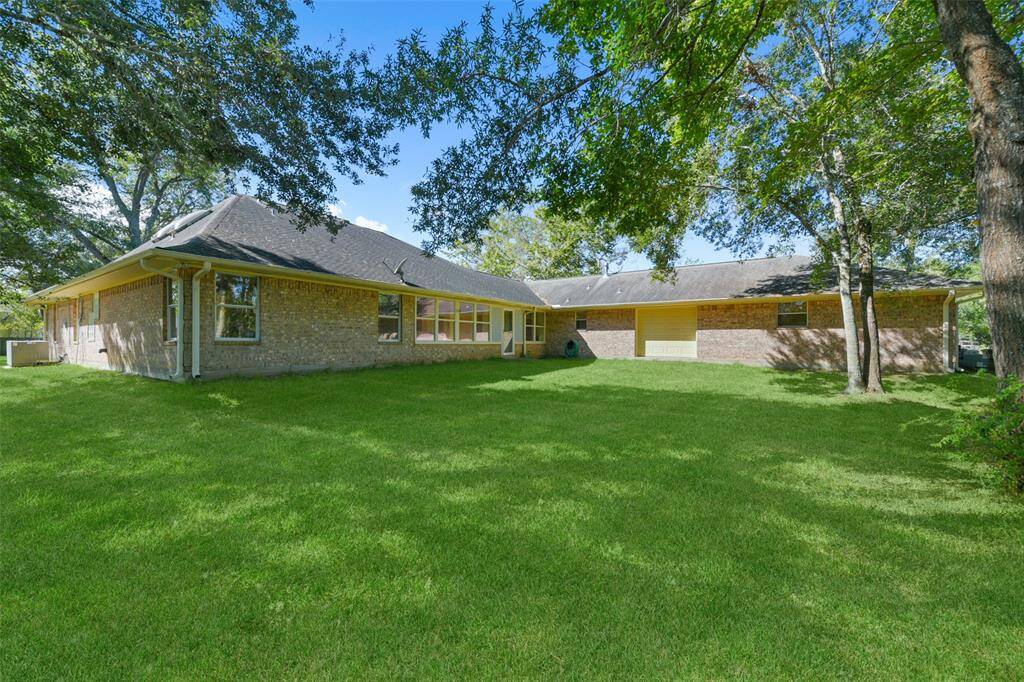 The view from the back of the home shows the storm door that leads out from the family room, plus the rear bay door on the extra large garage workshop area, as well as the grassy backyard space that gives way to a wooded wonderland just beyond.