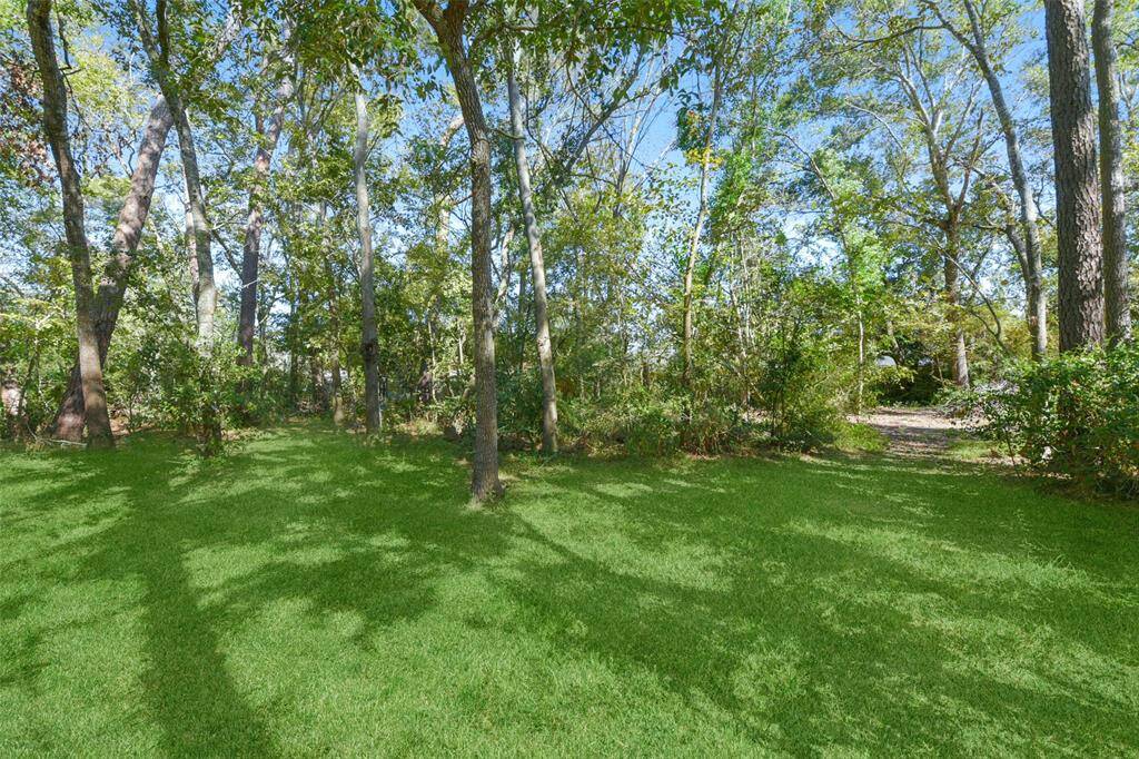 The view from the back of the home shows the storm door that leads out from the family room, plus the rear bay door on the extra large garage workshop area, as well as the grassy backyard space that gives way to a wooded wonderland just beyond.