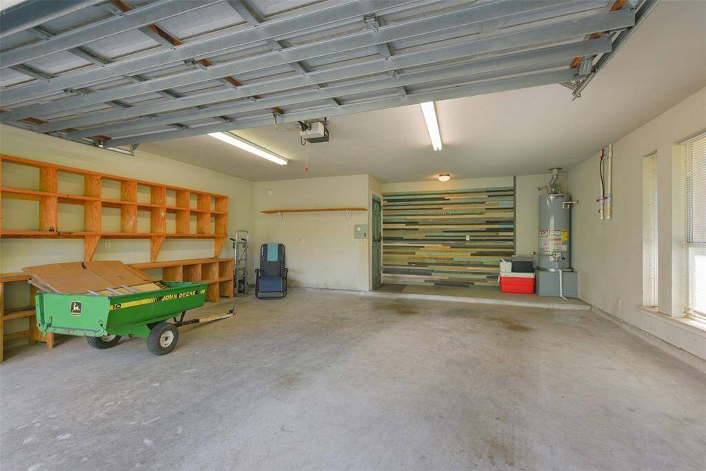 With all of the storage space in the workshop, the 2-car garage can stay uncluttered and be used for parking! Note the auto garage door opener, wood plank accent wall, and bold-painted turquoise door that opens into the dining area and kitchen.