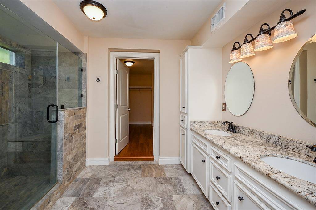 Master bathroom as you enter from the bedroom.  The luxurious master bathroom features a spacious walk-in shower, granite vanity, double sinks, and beautiful tile floors.  The bathroom leads into a spacious master closet.