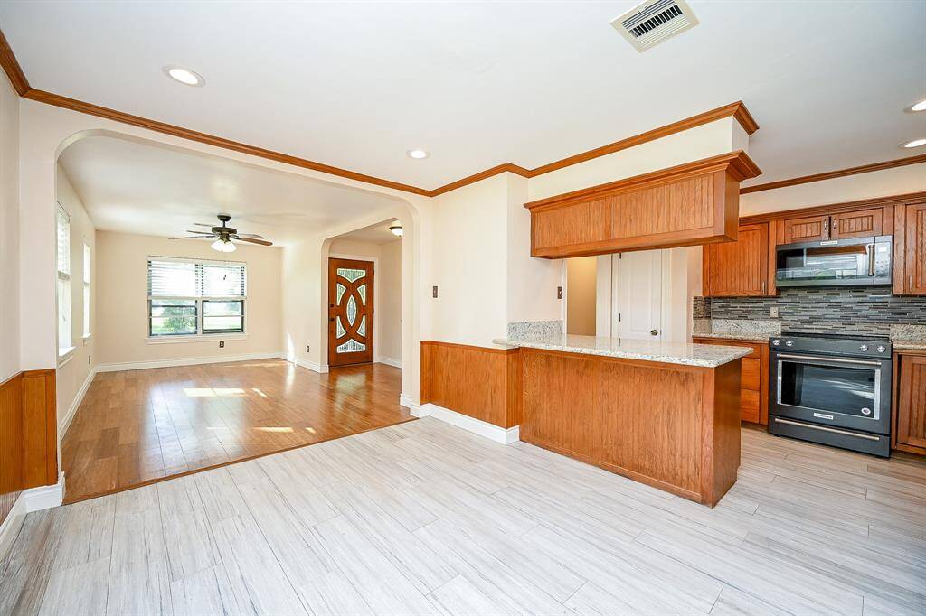 Wainscoting and cabinets add to the warmth and charm of the kitchen and large breakfast area.  Note the bar for extra seating and the wood-look tile for a high-traffic area!