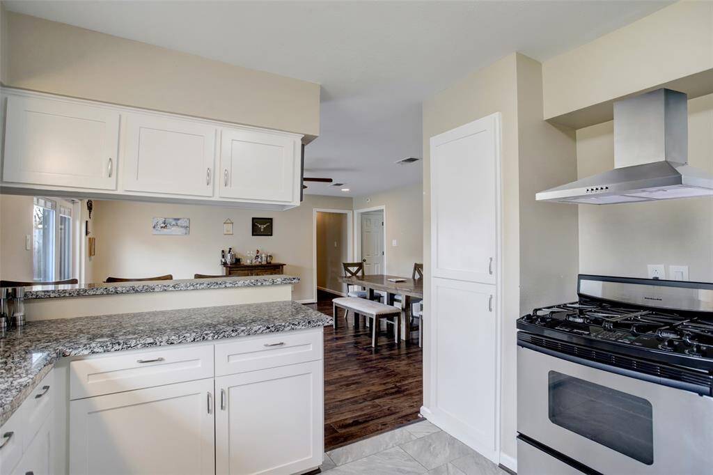 Gas stove! Stainless Steel Vent hood installed in 2025. Extra vertical cabinets used as a pantry area.