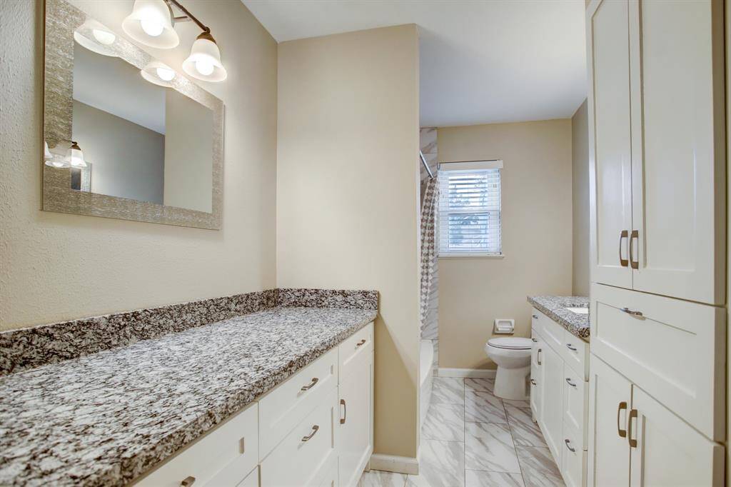 View of remodeled guest bathroom. Lots of storage space for your linens and toiletries. Granite countertops and 2 vanity areas.