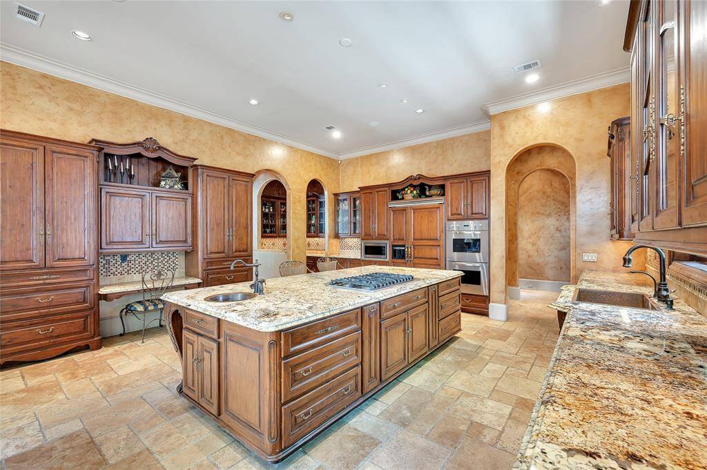 The kitchen is equipped with a 6-burner Viking gas cooktop, Thermador built-in wall microwave, Viking double wall ovens, 2 paneled Viking dishwashers, paneled Viking refrigerator and freezer with a built-in ice maker, hammered copper sink, coordinating prep sink, oil-rubbed bronze faucets, and a hot water faucet. Also, note the built-in letter-writing station and access to the wet bar.