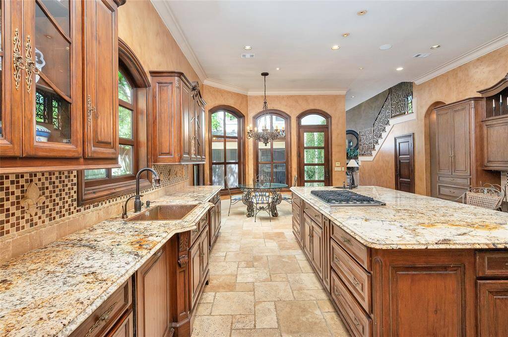 Additional features of the kitchen include travertine tile flooring, 11” baseboards, recessed and art lighting, surround sound, and double crown molding. Open to the breakfast area, multiple arched windows provide ample natural light. The paneled interior wooden door pictured above opens to the large walk-in pantry.