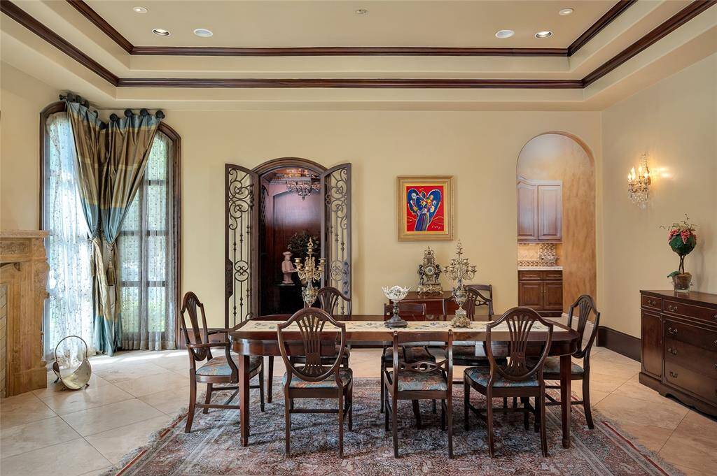 Another view of the formal dining room with arched wrought iron French doors that open to the wine cellar and an archway that leads to the butler’s pantry. This thoughtful layout allows for effortless dining and entertaining.