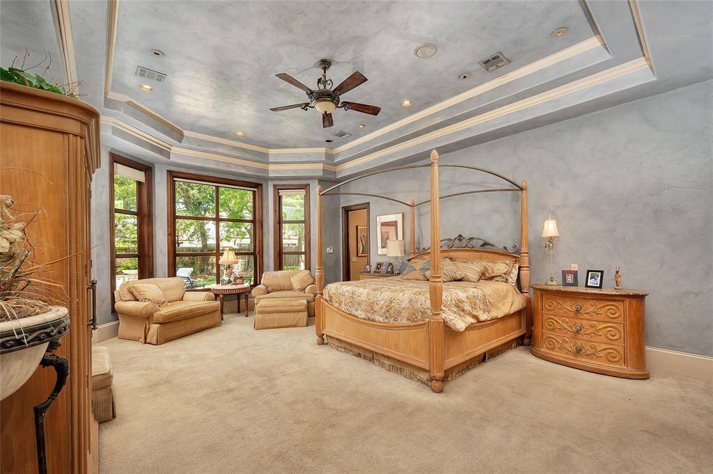 Located on the first floor, the primary suite features plush neutral carpet, 11” baseboards, custom faux painted light blue walls, double tray ceiling, recessed lighting with a decorative lighted ceiling fan, and surround sound. This space comes complete with a floor-to-ceiling bay window, cozy sitting area, backyard access, and a private office/flex room with stairs to the second floor.