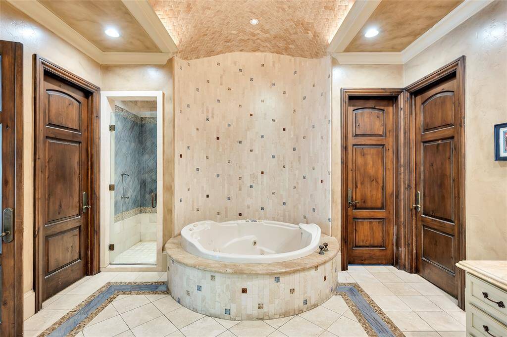 The primary bath also includes a large walk-in shower with glass door entry, a built-in bench, rainshower, two shower heads, handheld body sprayer, body sprays, and a shampoo niche. There is a separate water closet with a Toto toilet and two paneled wooden doors to access the custom walk-in closets that each feature hanging rods, dresser, accessory drawers, open shelving, and laundry hamper.