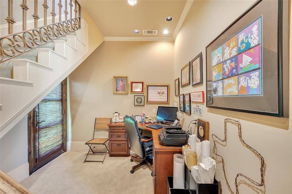Located off the primary bedroom, this quiet and cozy office space has exterior access to the side of the home along with stair access to the upstairs office area. Highlights include neutral carpet, tall baseboards, neutral wall paint, crown molding, and recessed lighting.