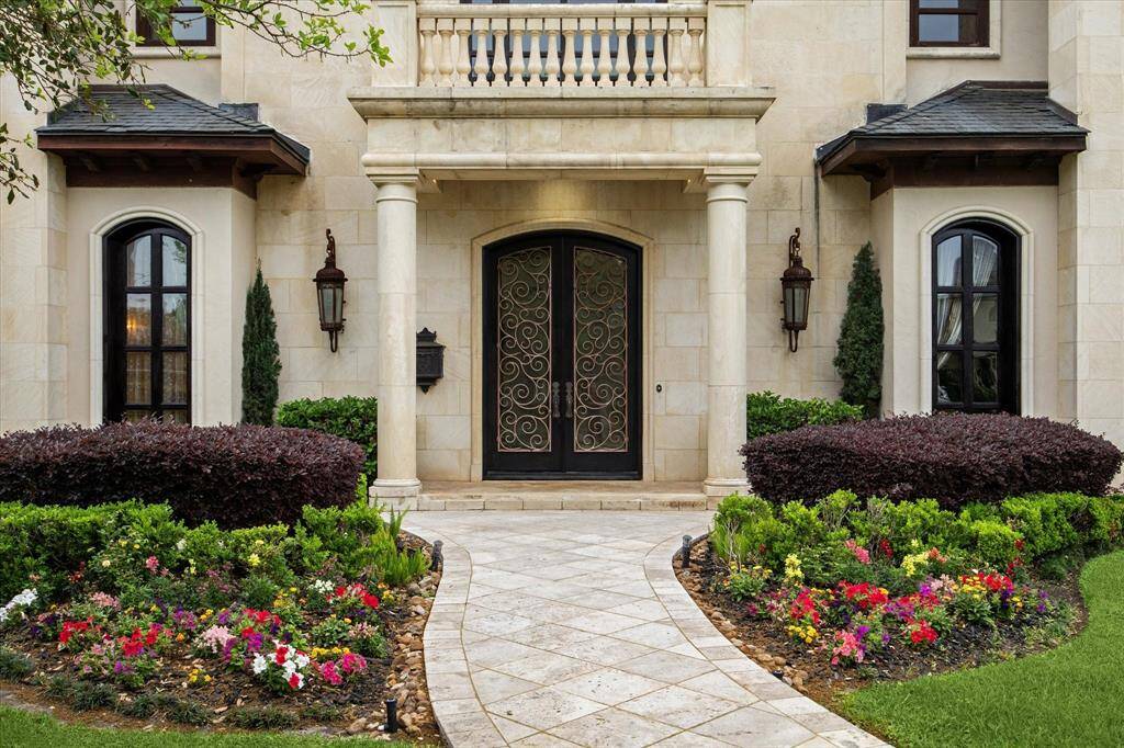 The beautifully manicured landscaping extends right up to the grand arched French door entrance flanked by stately columns.