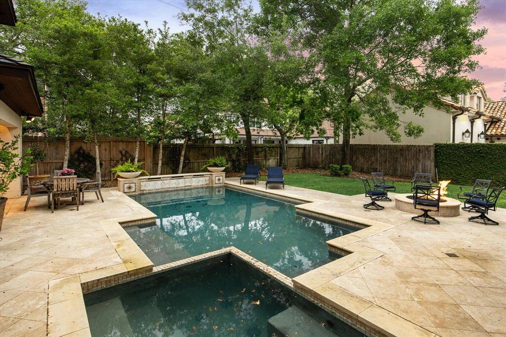The backyard pool area is enhanced by lush greenery with perimeter landscaping and a wooden privacy fence, making this the ultimate backyard retreat.P