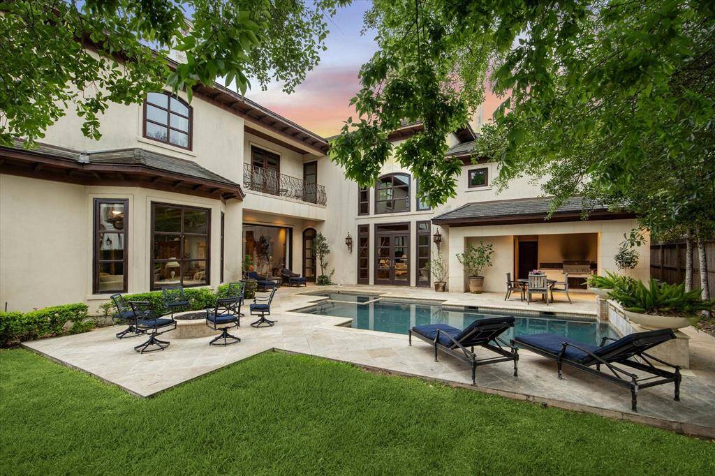 This photo showcases the resort-style backyard and striking back elevation of the home with many windows that showcase this captivating view.