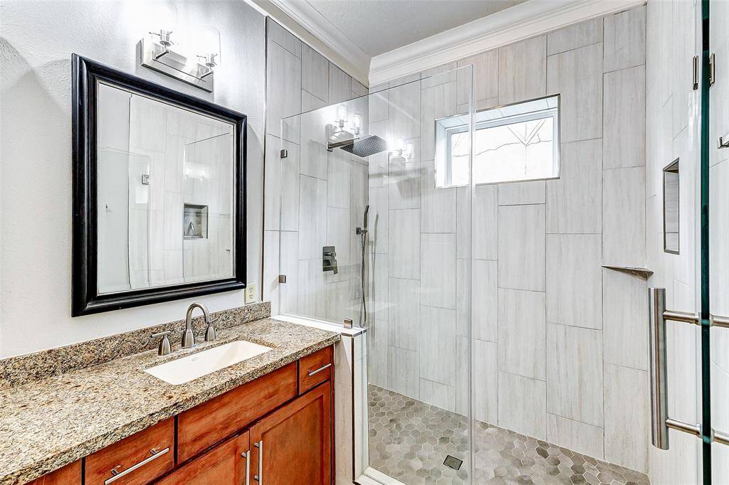 The large, frameless glass shower is a standout, with modern tilework, a rainfall showerhead, and built-in fixtures.