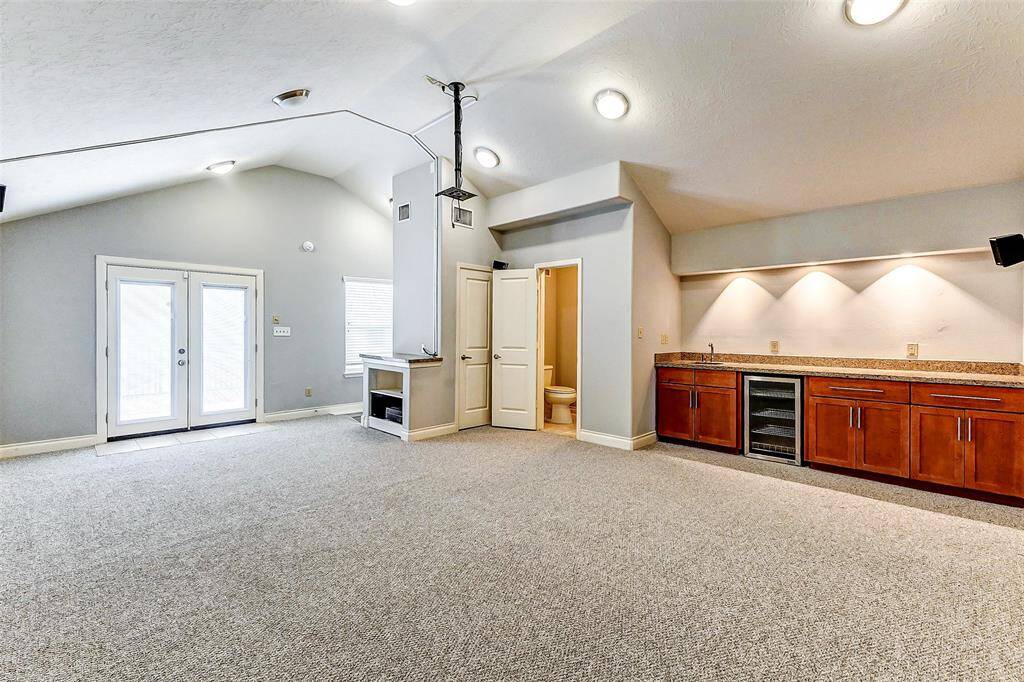 A built-in wet bar with granite countertops, custom cabinetry, and a mini fridge adds convenience for hosting.Other ways you can use thisspace could be a home office,playroom or game room.