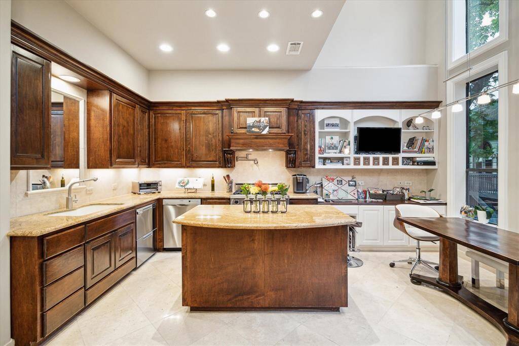 An expansive kitchen with plethora of sprawling counter space, storage, foliage views and balcony access overlooking serene pond.