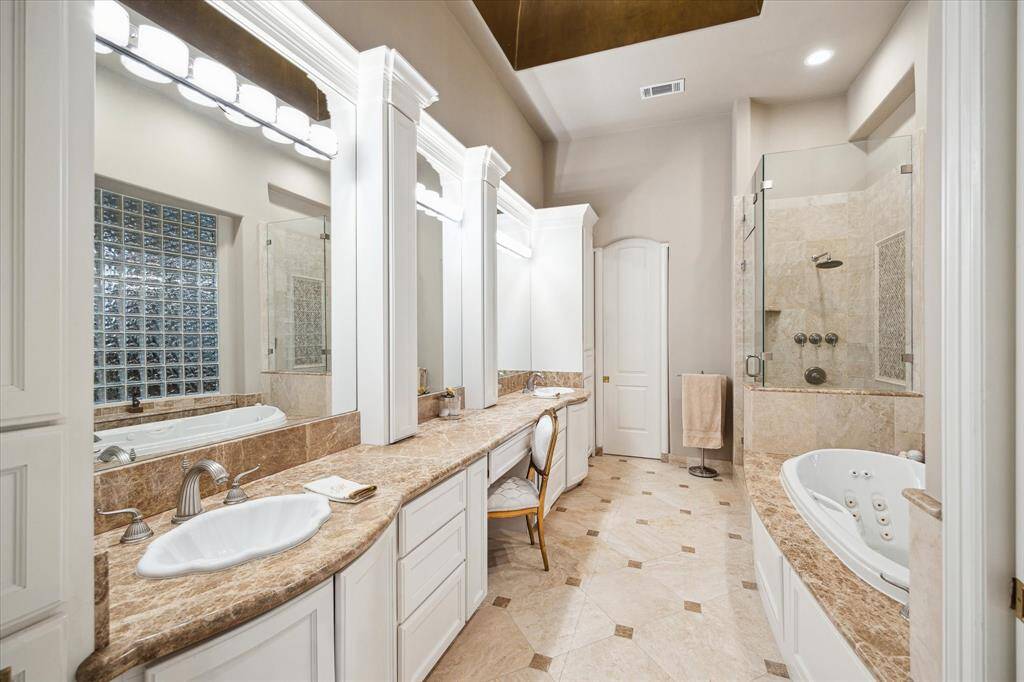 A stunning his and her primary bath with vanity, jetted soaking tub, and seamless glass shower.