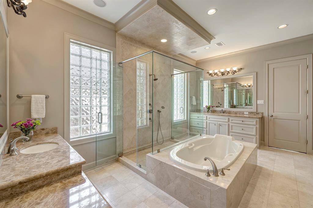 Luxurious primary bath finished in marble and featuring an extra spacious shower